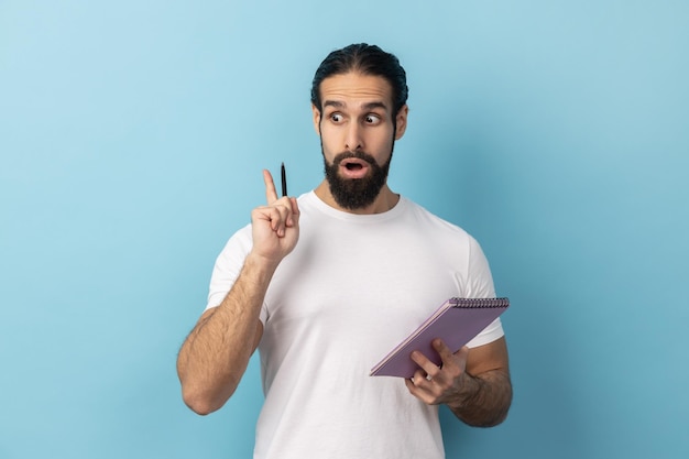 Man creative idea into notebook taking notes in paper raised arm keeps mouth open