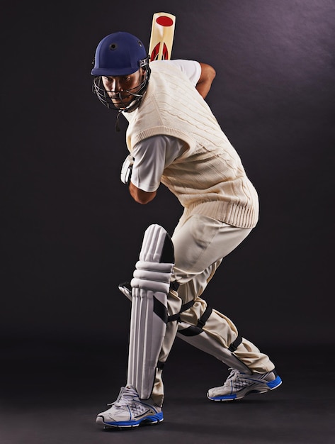 Photo man cricket and athlete with sports bat in studio for professional match competition or black background male person gear and helmet with mockup space or fitness training performance or game