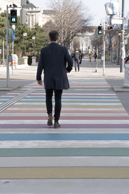 Foto uomo che attraversa la bandiera arcobaleno strisce pedonali a vienna