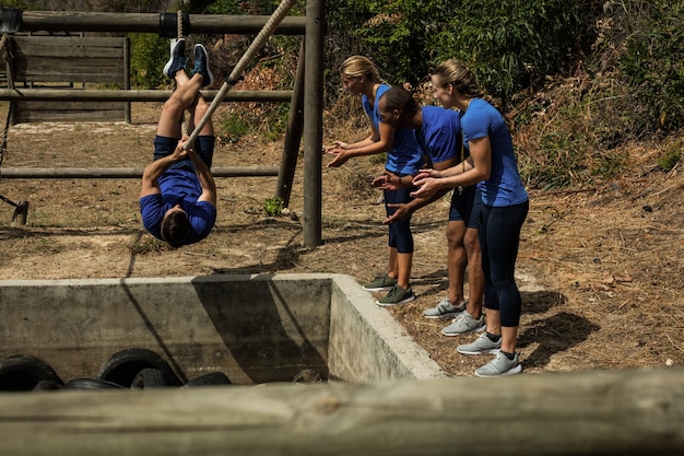 Man crossing the rope during obstacle course while people cheering him