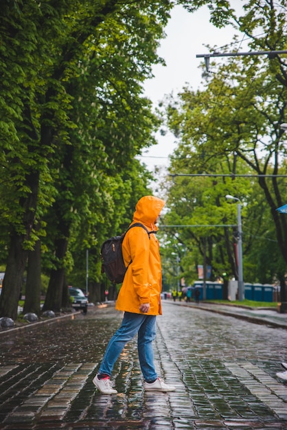 Man crossing street in yellow raincoat overcast weather