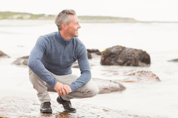 Man crouched down on a large rock