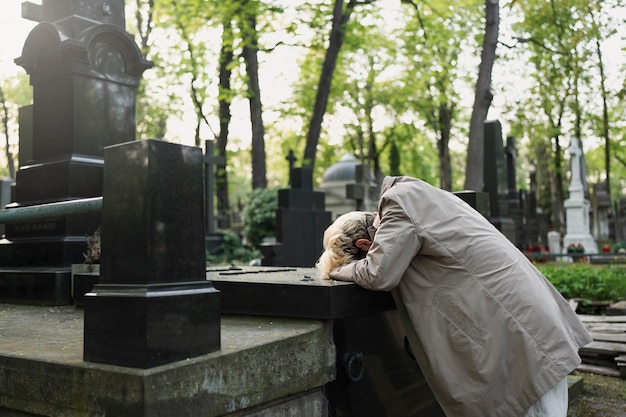 Foto uomo che piange su una tomba al cimitero