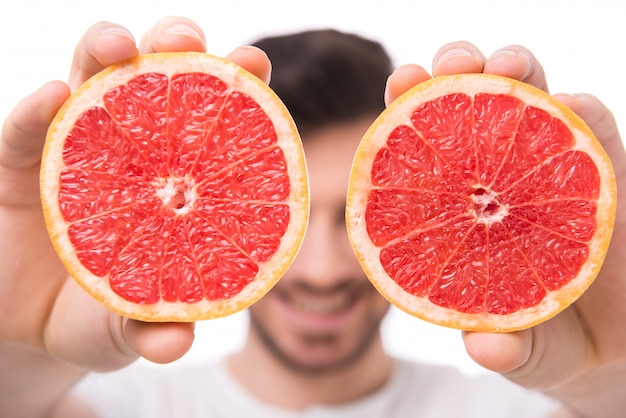 A man cut a grapefruit into two parts.