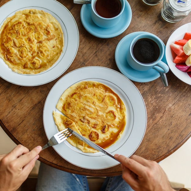 Man cuts banana pancakes breakfast in a hotel on bali