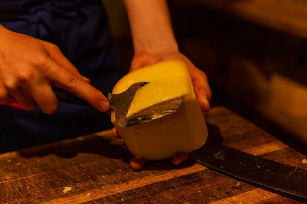 Un uomo taglia il formaggio in produzione. produzione agricola di prodotti lattiero-caseari. avvicinamento.