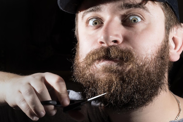 мужчина стригет бороду