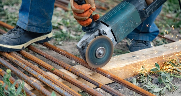 Man cuts off pieces of reinforcement using an angle grinder