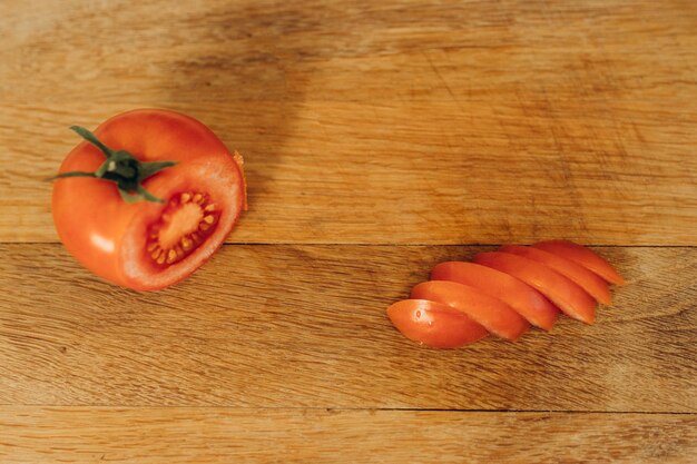 A man cuts a red tomato on a board