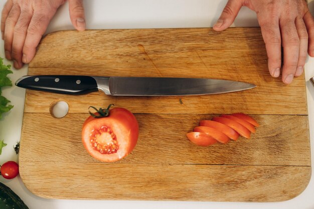 Photo a man cuts a red tomato on a board