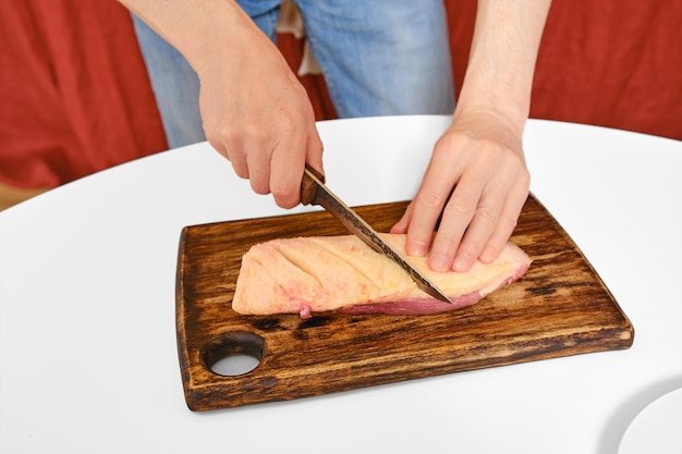 Photo man cuts the skin on a duck breast