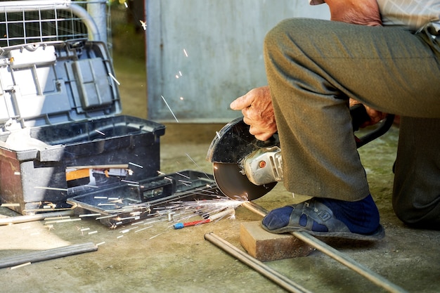 Foto un uomo taglia un tubo di titanio con una smerigliatrice.