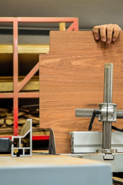 A man cuts wood on a circular saw in a joinery band saw holding a plank