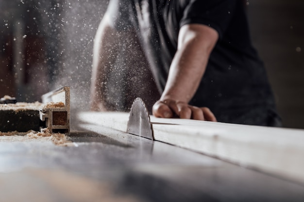 A man cuts wood on a circular saw in a joinery