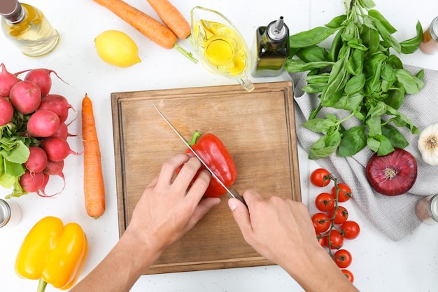 Man cutting bell pepper on wooden board