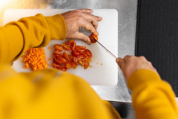 Man cutting cherry tomatoes in his kitchen