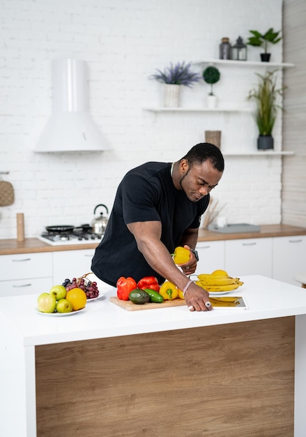 Man cutting fruit on a counter in a black shirt A man in a black shirt cutting fruit on a counter