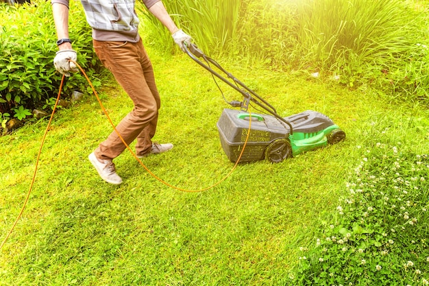 뒤뜰에 잔디 깍는 기계와 푸른 잔디를 절단하는 사람
