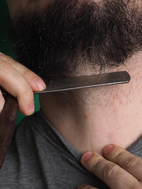 A man cutting his beard with a razor blade.