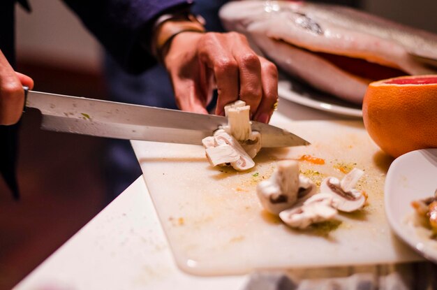 Photo man cutting mushrooms on board