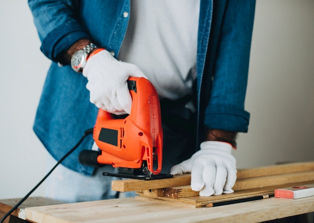 Man cutting a plank with a jigsaw machine