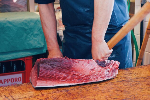 Man cutting raw tuna on table