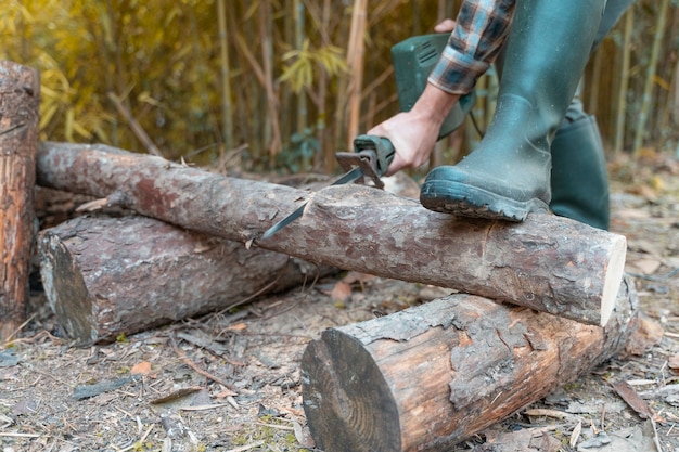 Uomo che taglia con sega elettrica polvere e movimenti taglialegna seghe albero con motosega su segheria