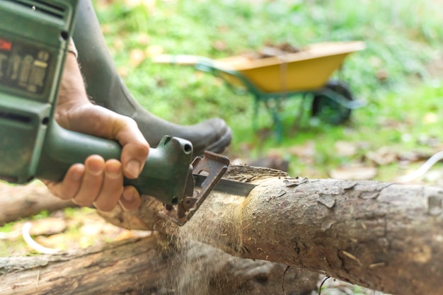 Foto uomo che taglia con sega elettrica polvere e movimenti taglialegna seghe albero con motosega su segheria