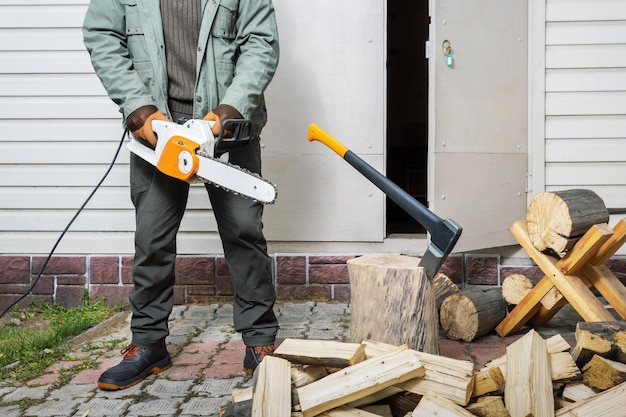 Man cutting wood with chain saw preparation firewood for heating the house