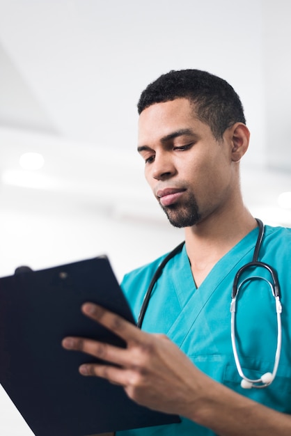 Man in a cyan colored dental coat taking notes