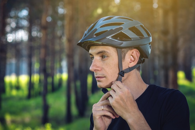 Фото Велосипедист человека носит шлем спорта серый на его голове на заднем плане зеленой природы.