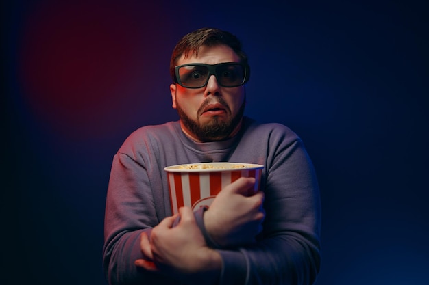 A man in d glasses and popcorn is watching a movie high quality photo
