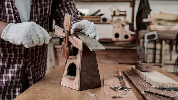 Man dagelijkse levensstijl thuis. Houtbewerking en doe-het-zelf vintage houten vogelhuisje voor tuindecoratie. Timmerman en ambachtsman workshop.