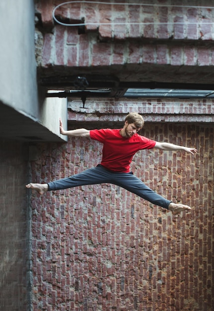 Photo man dancer jumping up high on wall background