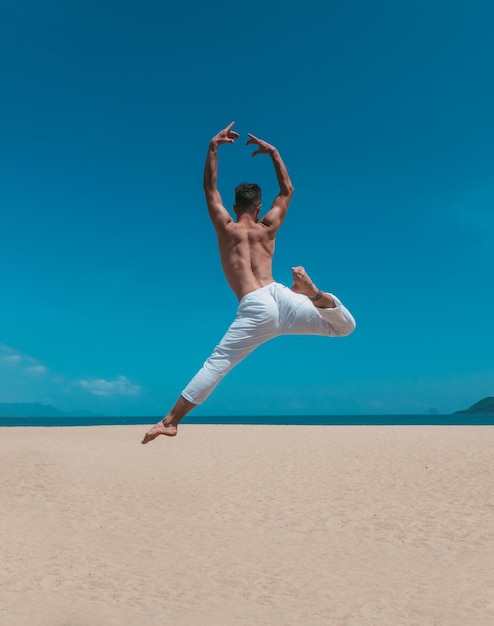 Uomo che balla danza contemporanea sulla spiaggia