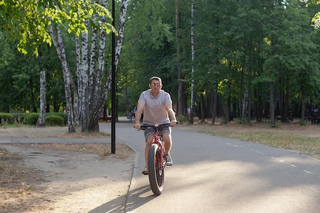Un uomo con gli occhiali scuri va in bicicletta attraverso un parco pubblico sport e tempo libero ciclista