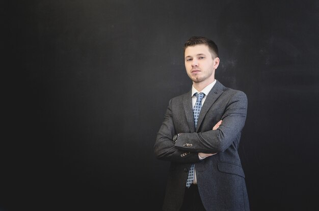 Man in a dark suit looks at the camera on a black background