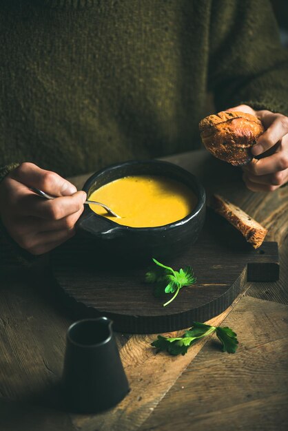 Man in dark sweater eating sweet corn soup from bowl