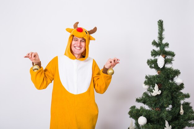 Man in deer costume decorating xmas tree on white wall