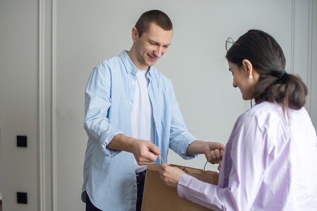 A man delivers a parcel in a craft package a girl accepts a package from a courier