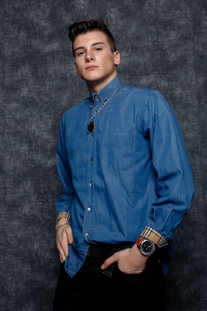 Man in denim shirt, arms on hips, gray background. People lifestyle concept. Mock up copy space. Straightening sleeves looking aside. hands on the belt