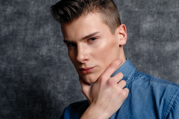 Man in denim shirt, arms on hips, gray background. People lifestyle concept. Mock up copy space. Straightening sleeves looking aside. serious, keeps the chin