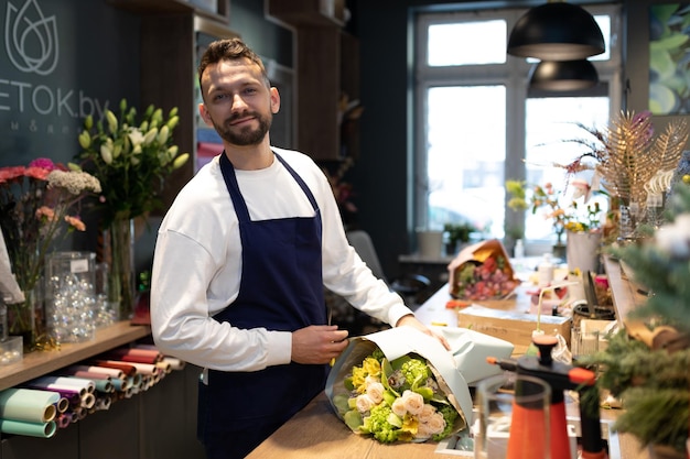 L'uomo designer di mazzi di fiori sul posto di lavoro crea una composizione floreale