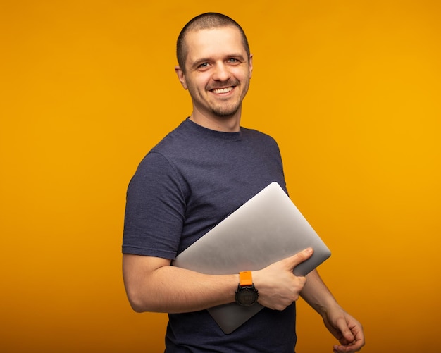 Man developer or freelancer or designer holding laptop standing at orange background