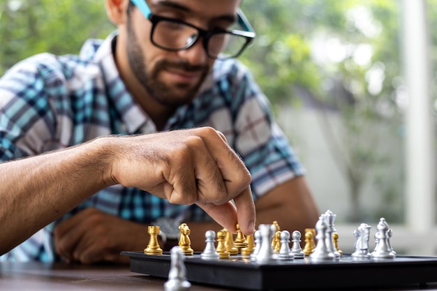 Man developing chess strategy, playing board game. Man thinking chess figure with team strategy and leadership concept. Clasped hands planning strategy with chess figures on table.