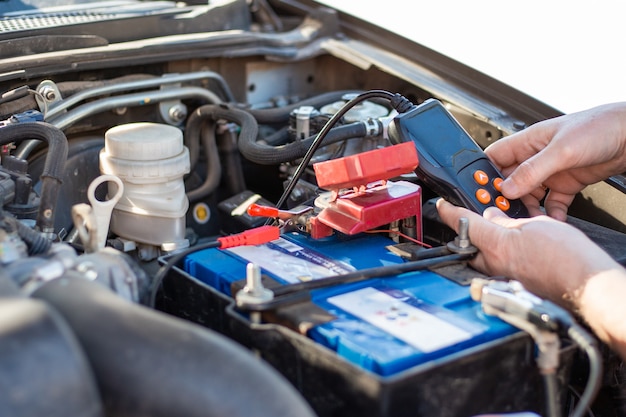 A man diagnoses a car battery with a tester, close-up. Battery repair and replacement.