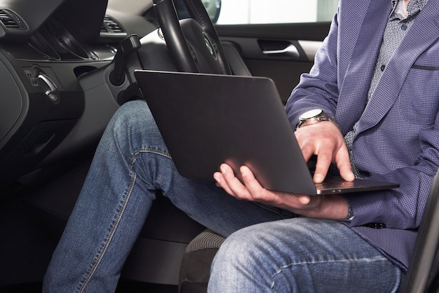 車のサービスで運転席に座っているコンピューターで車を診断する男