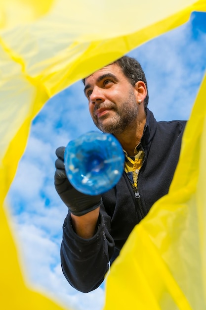 Man die afval op het strand opraapt Ecologie vervuiling van de zee die het zand van kunststoffen schoonmaakt