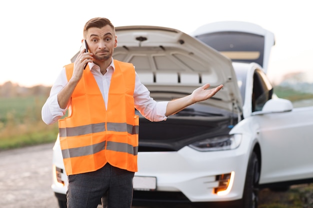 Man die auto-hulpdiensten belt omdat zijn elektrische auto kapot is