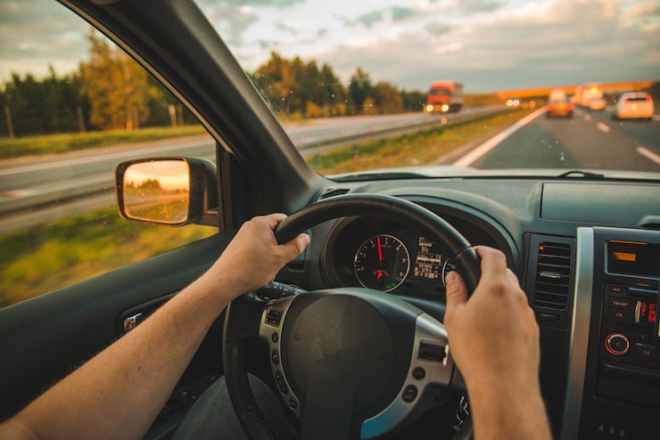 man die auto rijdt langs de snelweg op een road trip bij zonsondergang
